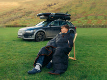 ADB - TentBox Synthetic Down Blanket wrapped around person in field, in front of TentBox roof tent