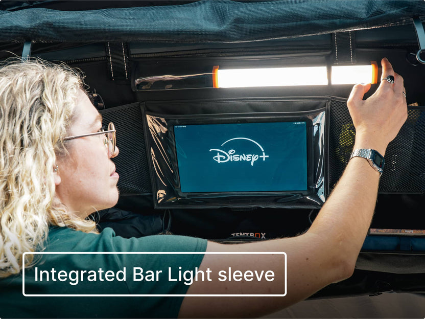 Person installing the LED Bar Light in the Storage Pocket compartment, with a tablet inside the tablet holder visibly showing the Disney+ logo. Text overlay reads 'Integrated Bar Light sleeve'.